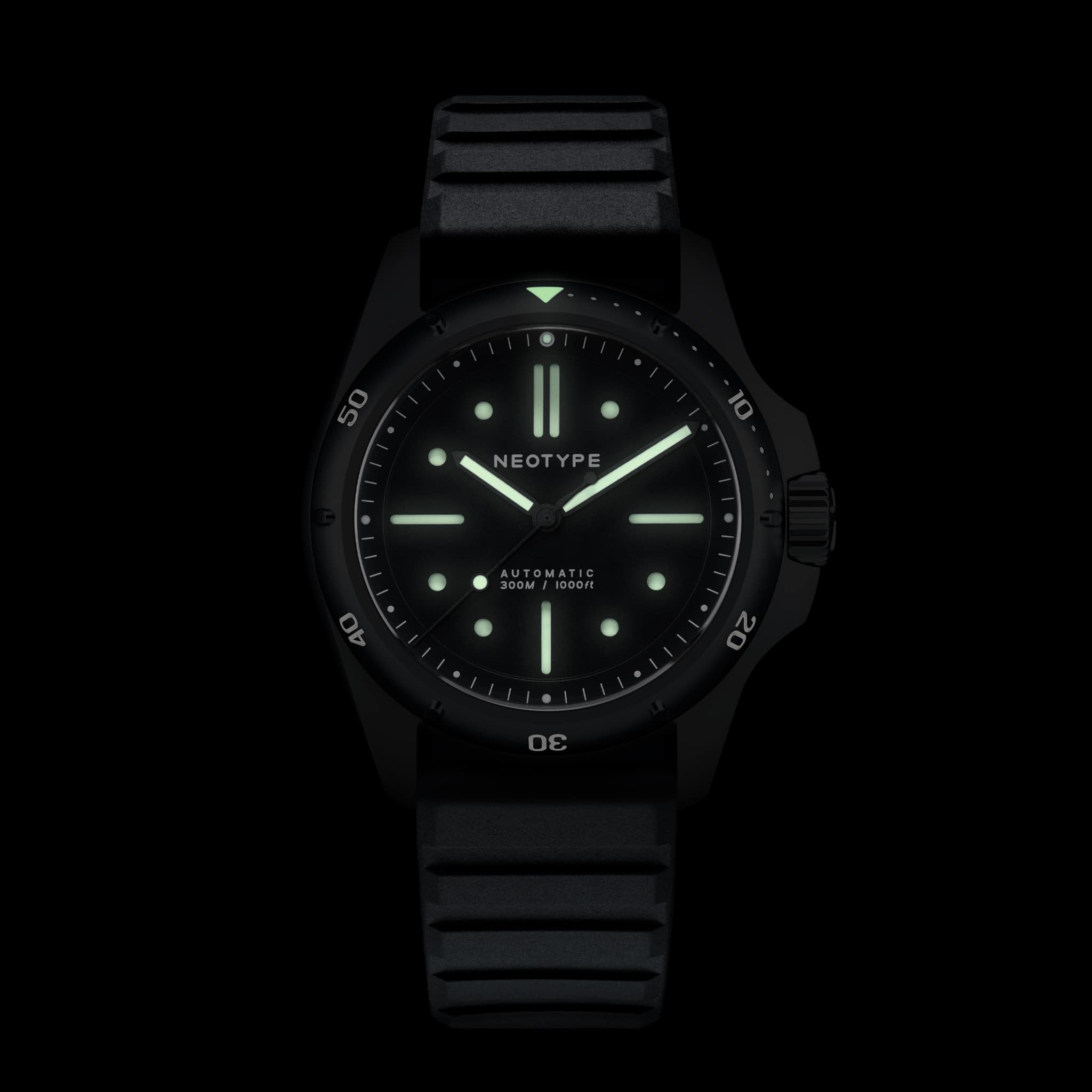 Montre de plongée Neotype Watches en acier PVD noir, vue de face dans l’obscurité, mettant en avant les effets lumineux du cadran.