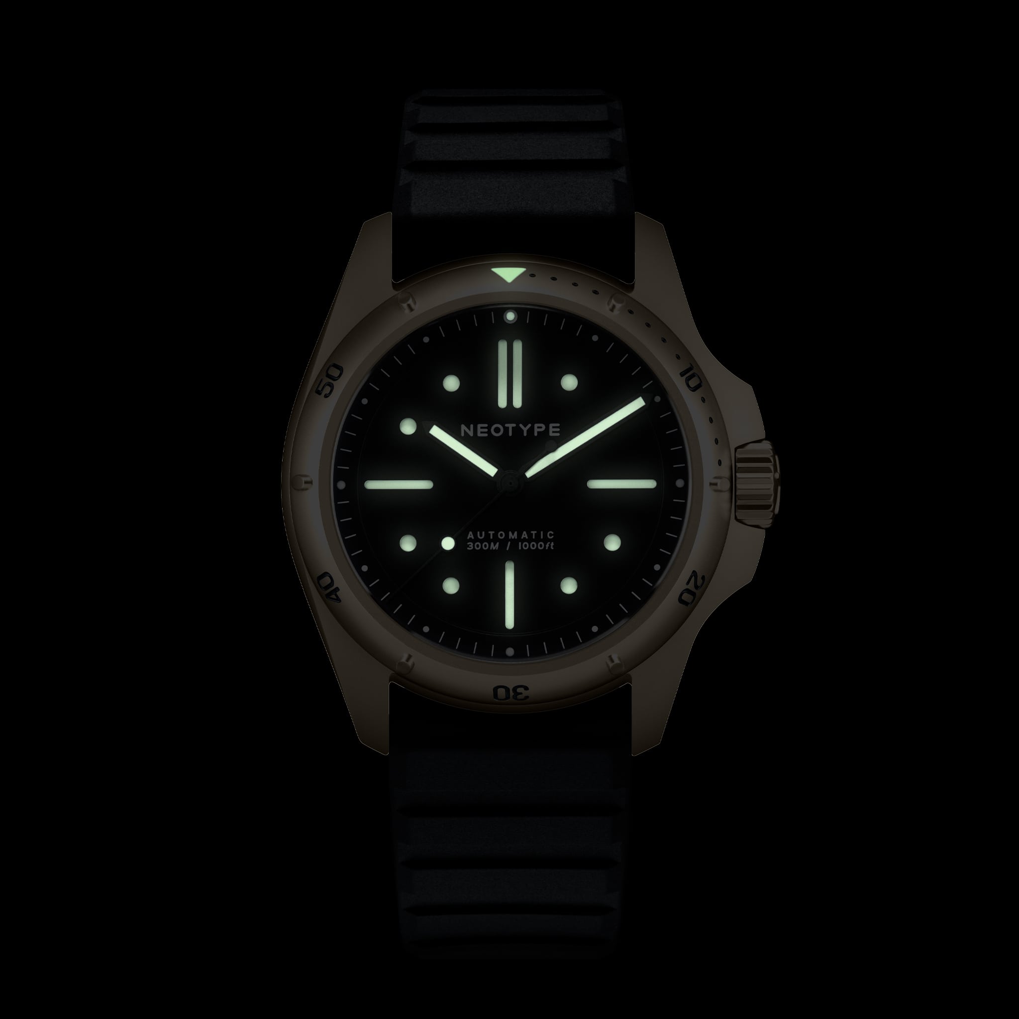 Montre de plongée Neotype Watches en acier PVD or, vue de face dans l’obscurité, mettant en avant les effets lumineux du cadran.