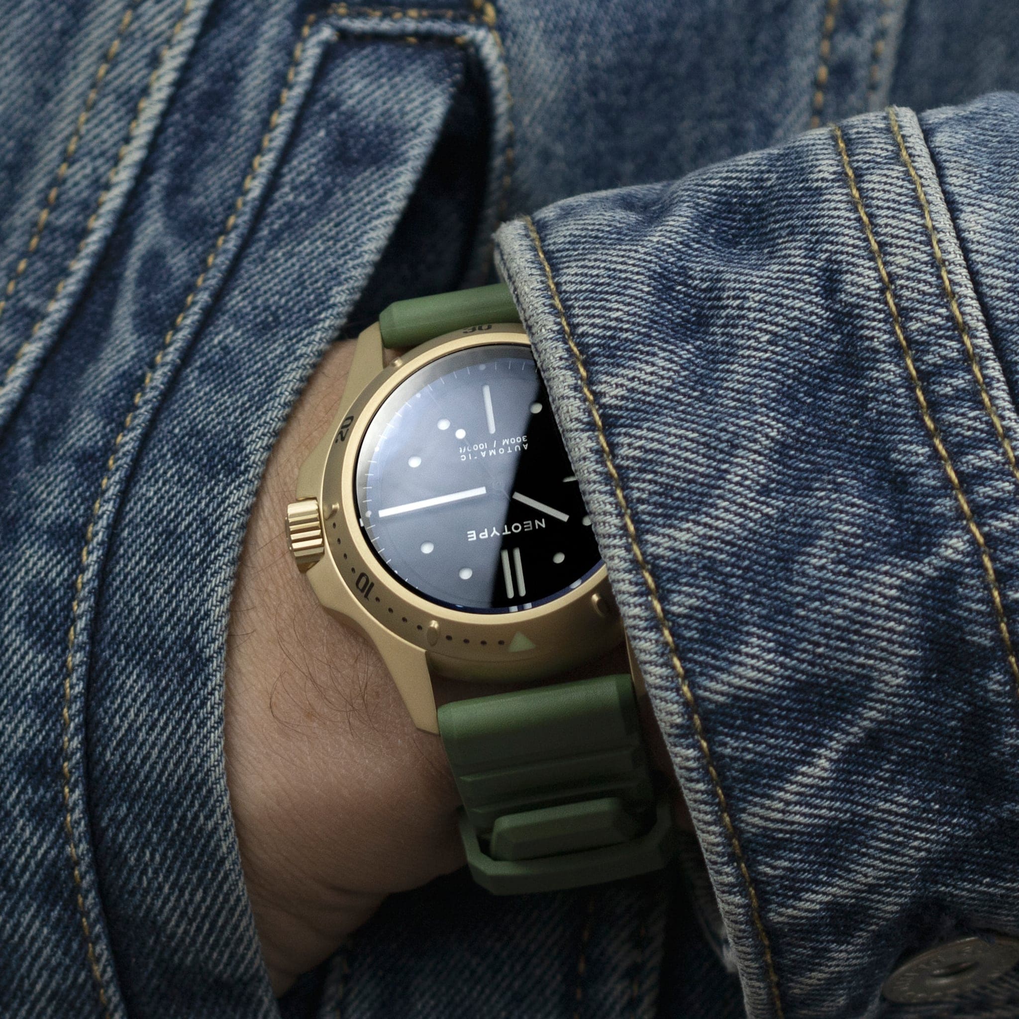 Bracelet FKM de Neotype Watches en caoutchouc fluocarboné vert, photographié avec son emballage, soulignant son design soigné et moderne sur une surface claire.